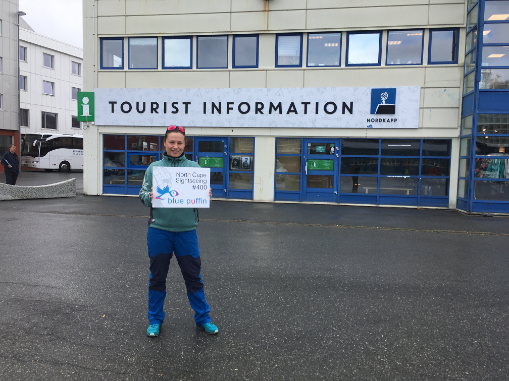 Treffpunkt - North Cape Sightseeing-Tour - Monika mit Schild vor der Touristeninformation, Honningsvåg, Norwegen